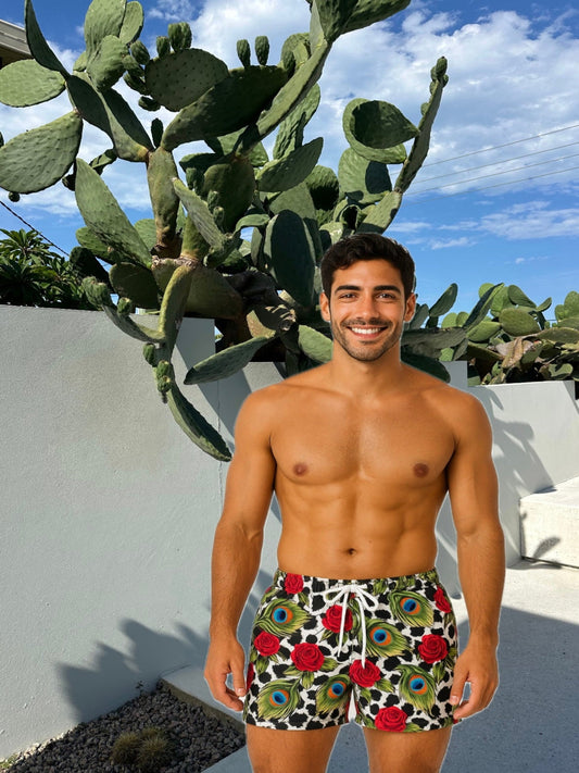 Man wearing colorful swim trunks standing in front of a cactus plant.